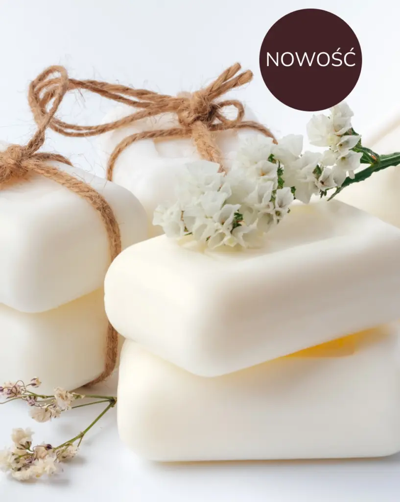 Pięć mydełek z kości słoniowej, przewiązanych sznurkiem, ułożonych jest artystycznie, a wokół nich rozłożone są delikatne białe kwiaty. Scena jest czysta i świeża.